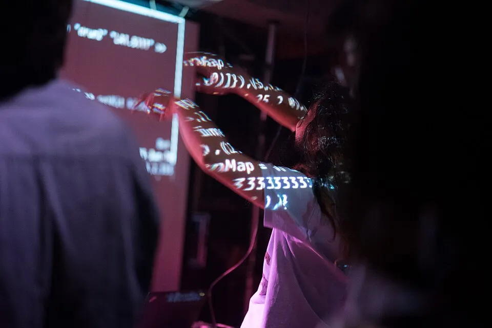 A dancer performing with live-coded music projected onto their arms